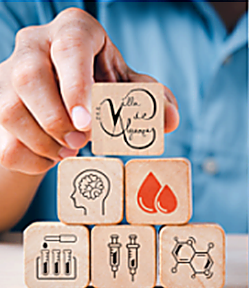 Mano colocando cubos de madera con iconos de salud y el logotipo del IES Villa de Alguazas